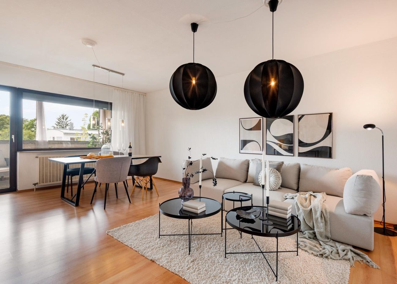 Nachher: dasselbe Wohnzimmer modern und hell eingerichtet, mit Sofa, Essplatz und schwarzen Pendelleuchten